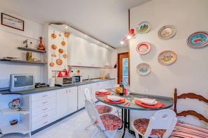 A compact kitchen with white cabinets, a microwave, and a dining area with a table set for two.