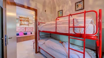 Une pièce avec un lit superposé, un banc en bois avec des coussins et un mur orné de tableaux.
