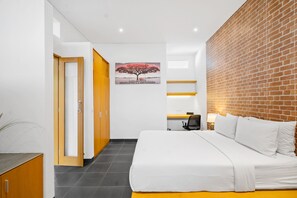 Une chambre moderne avec un grand lit, un mur décoratif en briques, un tableau et un bureau avec une chaise.