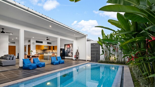 A modern indoor swimming pool area with a kitchen and living space. - Pasha Villa by Betterplace (Kerobokan)