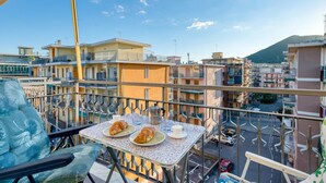 A balcony with a table set for two, two croissants, a cup, and a coffee pot. - Il Rifugio - Town Center Apartment with Balcony, Borghetto Santo Spirito, Italy (Borghetto Santo Spirito)