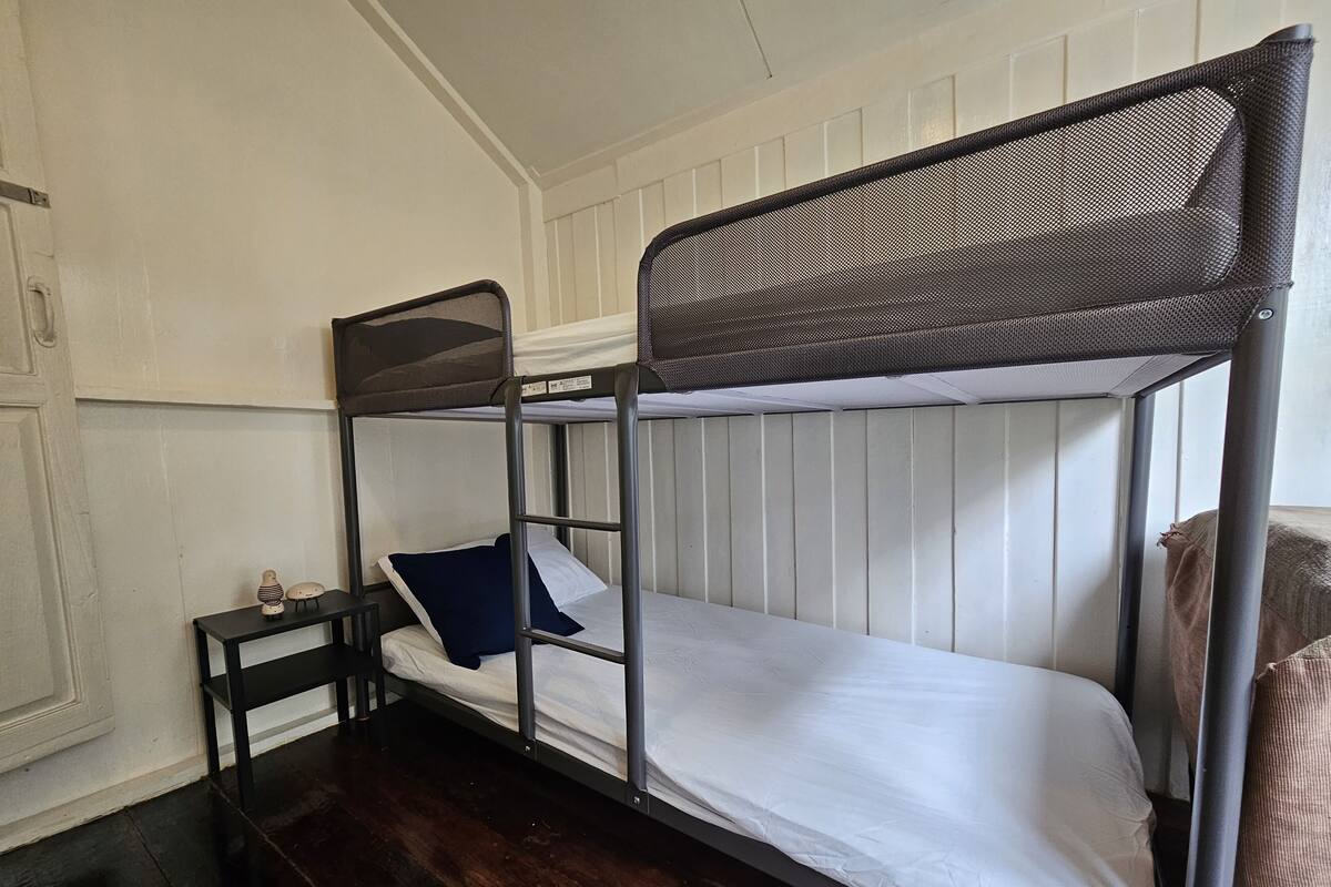 A bunk bed with a headboard, a bedside table, and a pillow.