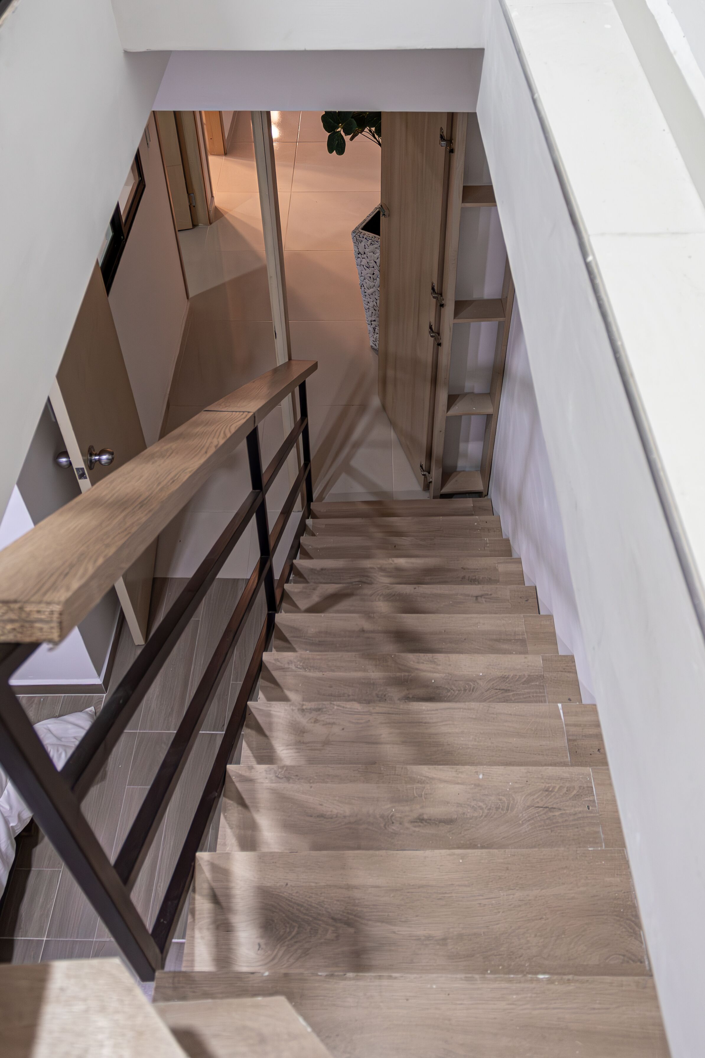 A wooden staircase with a metal railing leading to an upper floor.