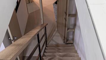 A wooden staircase with a metal railing leading to an upper floor.