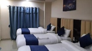 A hotel room with two beds, a ceiling fan, a night sky poster, and a window with blue curtains. - Hotel sara  (Janakpur)
