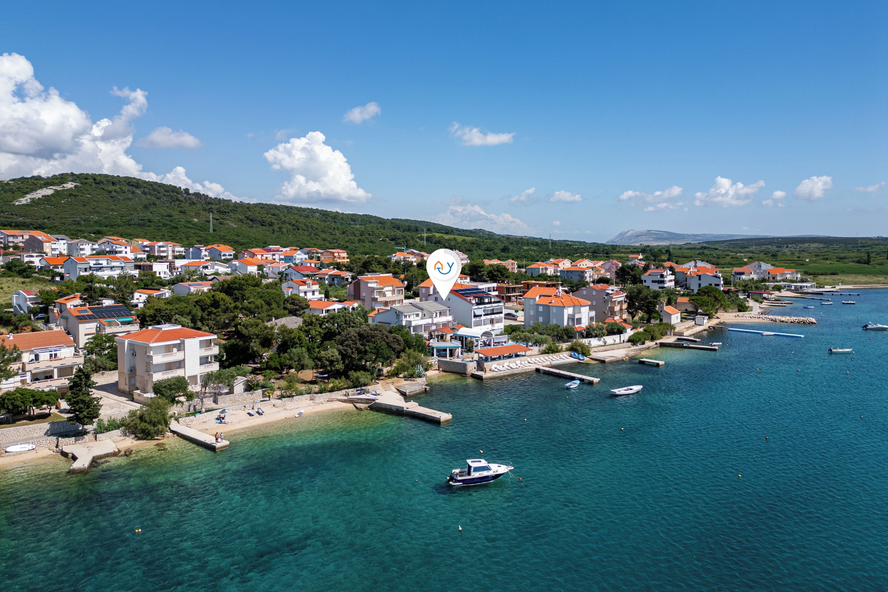Un pueblo costero con edificios, un puerto deportivo y aguas azules cristalinas.