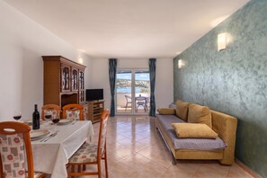 A living room with a sofa, a dining table with chairs, a TV, and a cabinet. - Family Resort Santa Maria II Apartment 2 (Novalja)