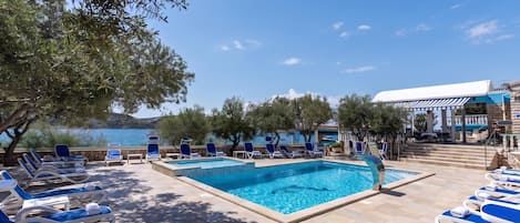Zona junto a la piscina con sillones de descanso y vista al mar.