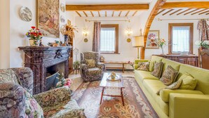 A living room with a fireplace, patterned furniture, and a green sofa. - Villa Paola Private Pool Gym in Chianti (Montespertoli)