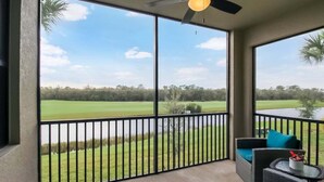 A balcony with a view of a golf course and a body of water.