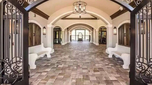 A spacious hallway with a tiled floor, white benches, and decorative iron gates.