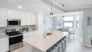 A modern kitchen with white cabinets, stainless steel appliances, and a large island with bar stools.