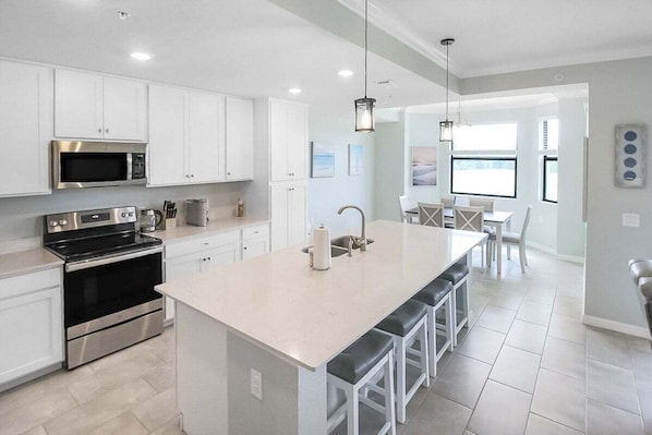 Una cocina moderna con armarios blancos, electrodomésticos de acero inoxidable y una isla grande con taburetes de bar.