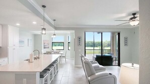 A modern kitchen with a central island, a dining area with a table and chairs, and a seating area with a sofa and a lamp.