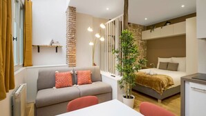 Un appartement moderne comprenant un canapé, une table à manger, un lit et une plante en pot.