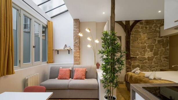 Un espace de vie compact comprenant un canapé, une table à manger, une plante en pot et un lit.