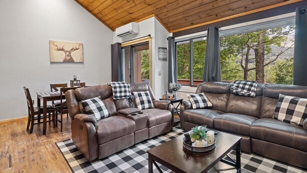 A modern living room with leather sofas, a dining table, and a checkered rug. - The Mountain Retreat - Loon Mtn - Pools - Views - Shuttle Service (Lincoln)