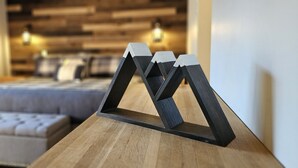 A modern bedroom with a wooden headboard, a tufted sofa, and a wooden nightstand with a geometric lamp. - The Mountain Retreat - Loon Mtn - Pools - Views - Shuttle Service (Lincoln)