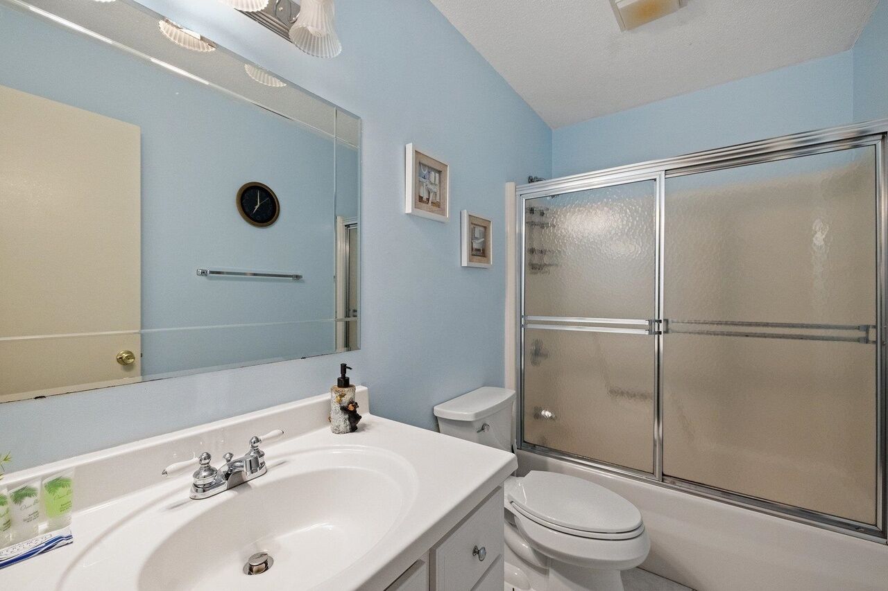 Une salle de bain avec un lavabo blanc, des toilettes, une douche en verre et un miroir.