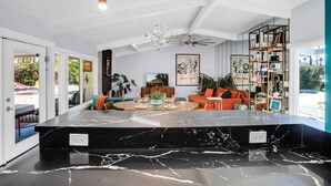 A modern interior with a marble countertop, a ceiling fan, and a bookshelf. - Luxury Escapade w/ Pool, Hot Tub & Mountain Views (Palm Springs)