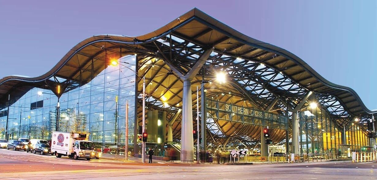 A modern train station with a distinctive curved roof and large glass windows.