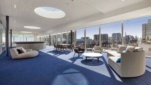 A modern lounge area with seating, a bar, and large windows offering a city view. - Modern 1B1B Artist APT * WFH Study (Melbourne)