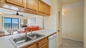 A kitchen with wooden cabinets, a double sink, and a dishwasher.