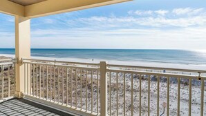 A balcony with a view of a beach and ocean.