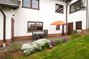 A house with a patio, a table with chairs, and an umbrella. - Apartment 'Am Tivoli' with Private Terrace, Private Garden and Wi-Fi (Hermeskeil)