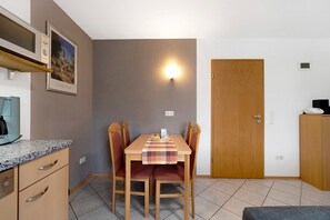 A dining area with a table, chairs, a microwave, a coffee maker, and a door. - Apartment 'Am Tivoli' with Private Terrace, Private Garden and Wi-Fi (Hermeskeil)