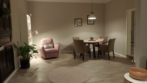 A dining area with a round table, chairs, a potted plant, a rug, and a hanging light fixture. - Holiday Apartment "Am Conradhof" with Private Terrace and Wi-Fi (Goch - Pfalzdorf)