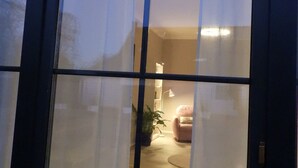 A room with a large window, a potted plant, a lamp, and a pink chair. - Holiday Apartment "Am Conradhof" with Private Terrace and Wi-Fi (Goch - Pfalzdorf)