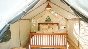 A tent with a bed, a hanging light fixture, and a window. - Casa Parcha (Naguabo)