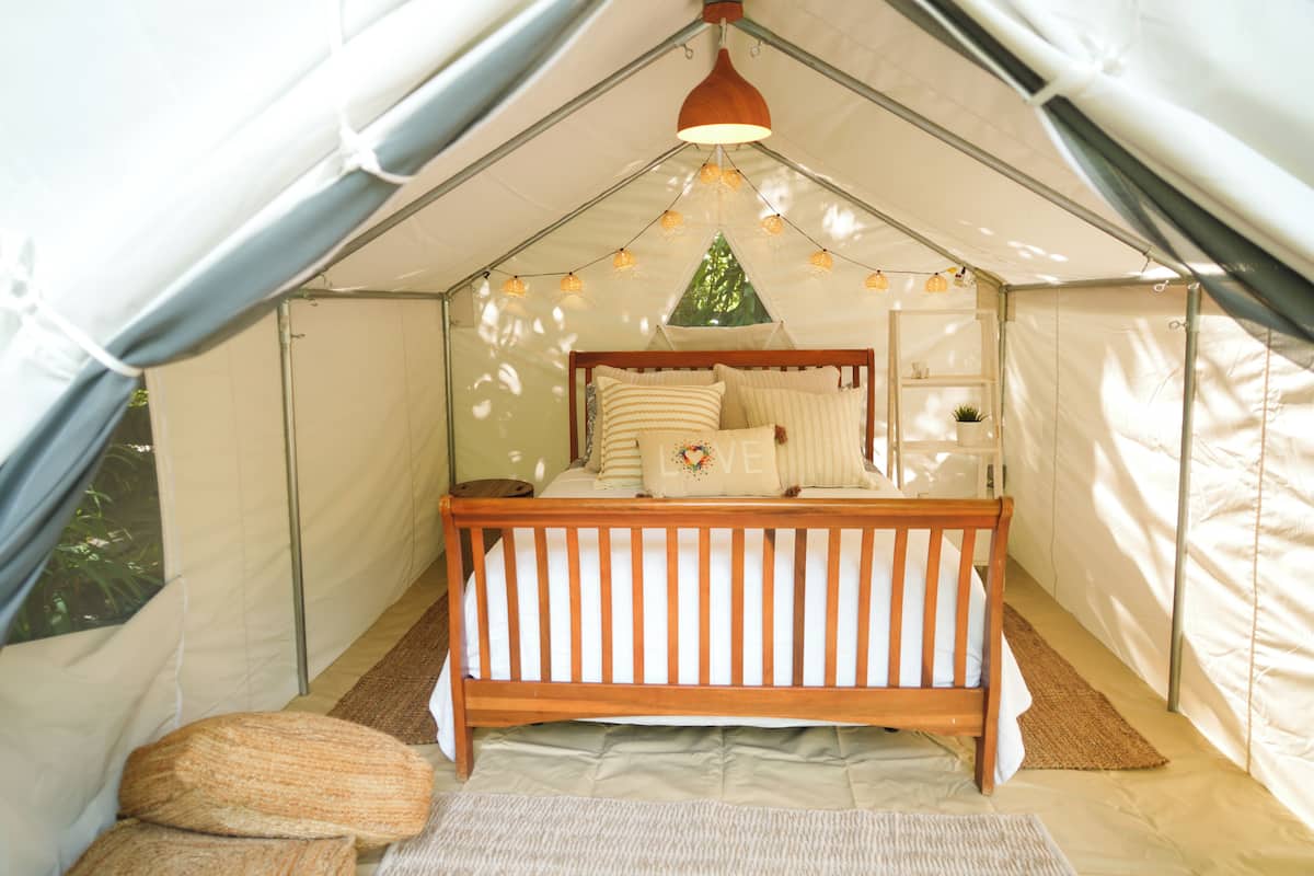 Una carpa con una cama, una lámpara colgante y una ventana.