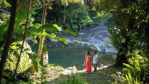 A couple standing by a lake with a natural backdrop and string lights. - Casa Parcha (Naguabo)