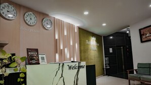 Un espace d’accueil avec des horloges, une pancarte « Bienvenue », une pancarte « Réception » et une pancarte « Hôtel Banana Tree ».