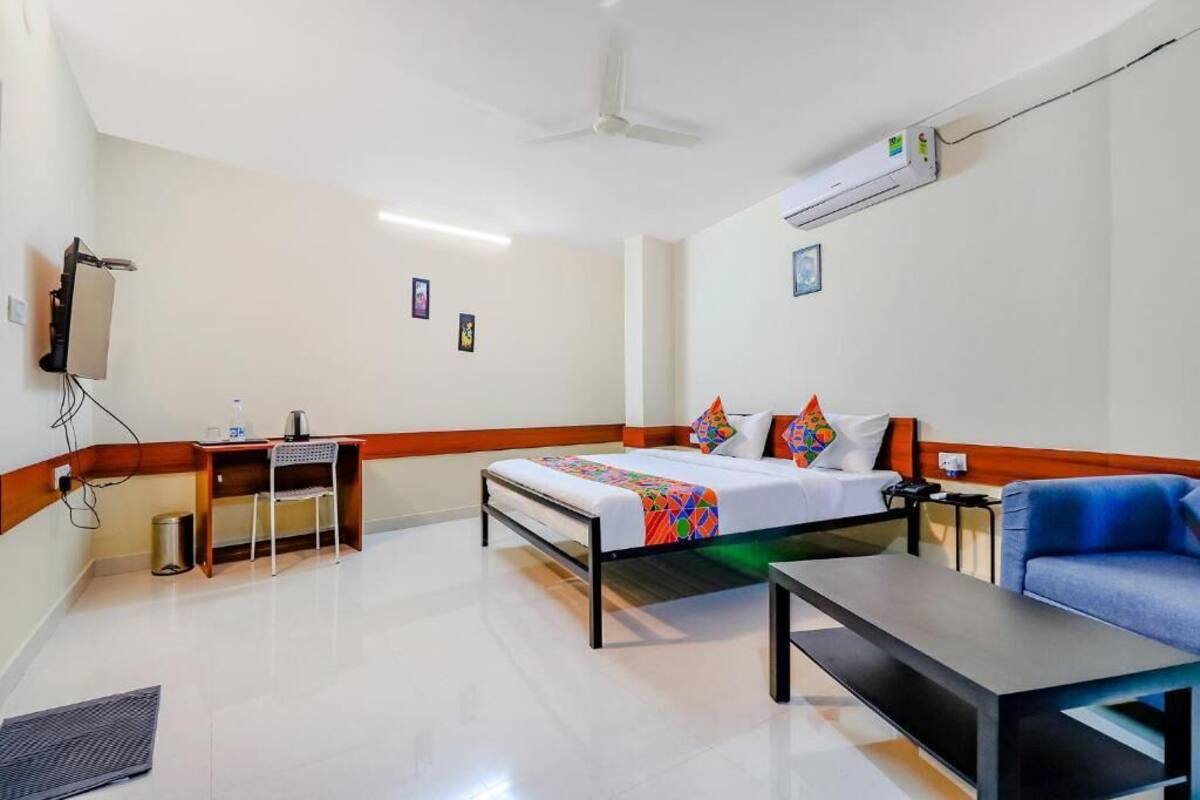 Quarto de hotel com uma cama, uma escrivaninha, uma cadeira, um sofá e um aparelho de ar condicionado.