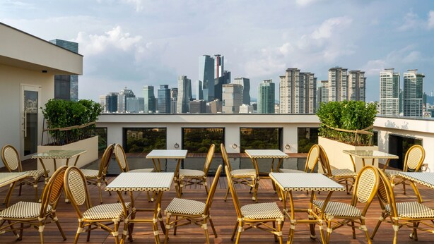 Una terraza en la azotea con mobiliario exterior y vistas a un horizonte urbano.