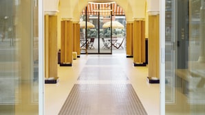 Un moderno vestíbulo de hotel con un espacio central abierto, puertas de vidrio y piso de baldosas.