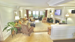 A spacious living room with a fireplace, comfortable seating, and a television mounted on the wall. - Riverwood Hutchinson Island (Stuart)