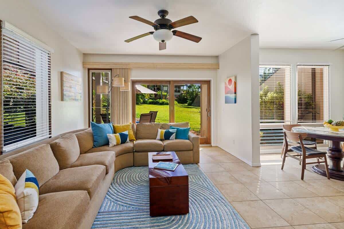 A spacious living area with a sectional sofa, a coffee table, and a ceiling fan.