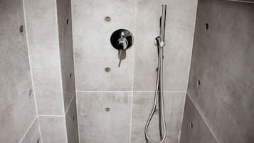A shower with a handheld hose and a wall-mounted control.