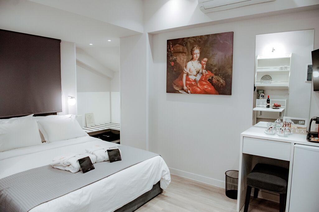 Habitació d'hotel moderna amb un llit ben fet, una taula de treball amb un mirall i un quadre a la paret.