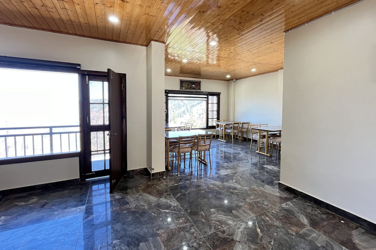 Una habitació àmplia amb sostre de fusta, grans finestres i un paviment de marbre.