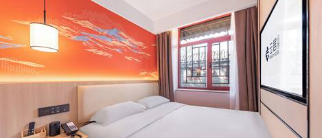 Een hotelkamer met een bed, nachtkastje, lamp en een raam met gordijnen.