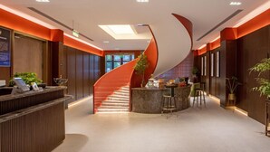 Eine moderne Hotelhalle mit Wendeltreppe, einer Rezeption und einer Bar.