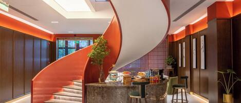 Un interior moderno con una escalera de caracol, una zona de cocina y taburetes de bar.