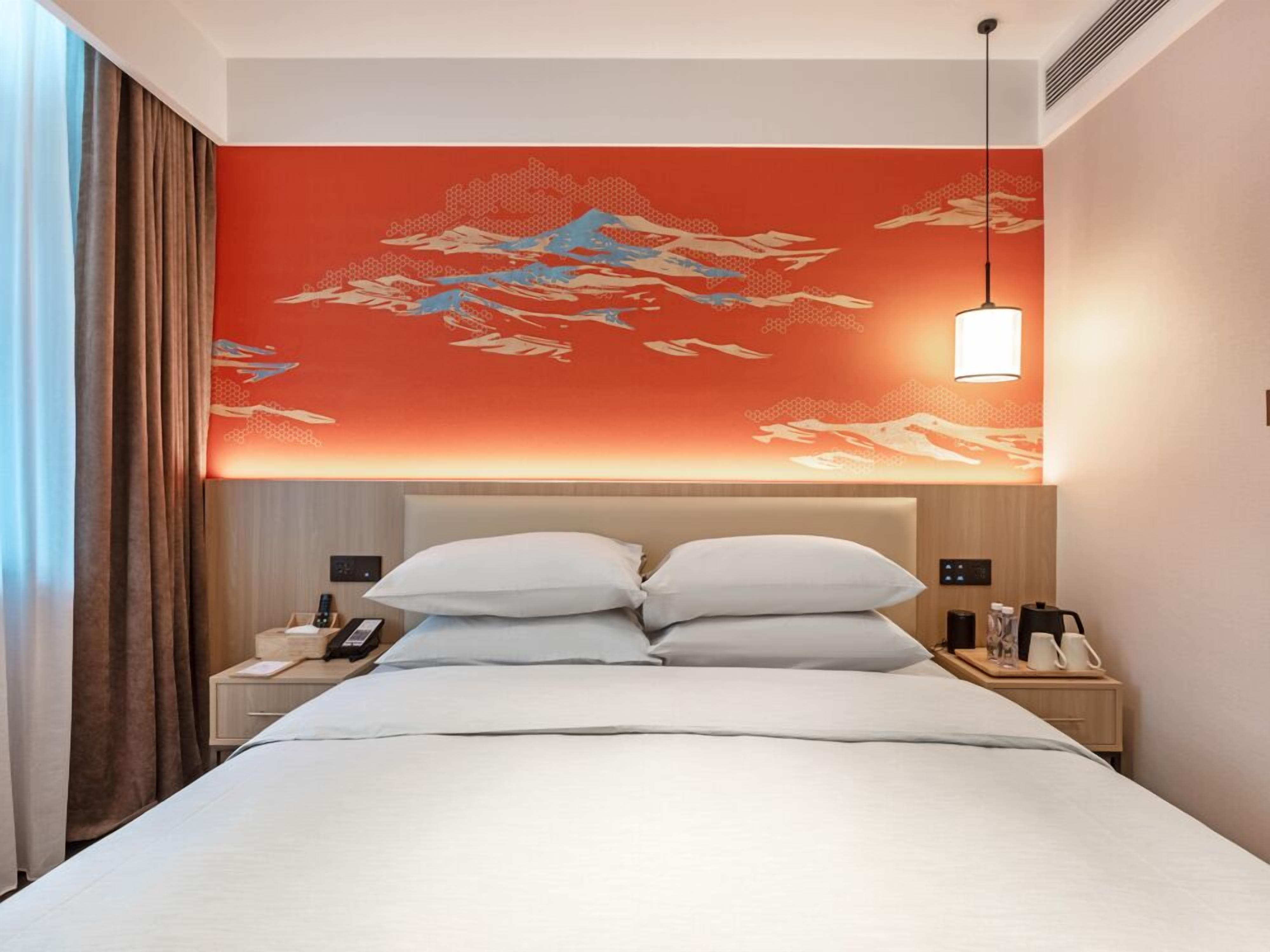 Ein Hotelzimmer mit einem Bett, Nachttischen, einem Telefon und einer Wand mit rotem und beigem Dekor.