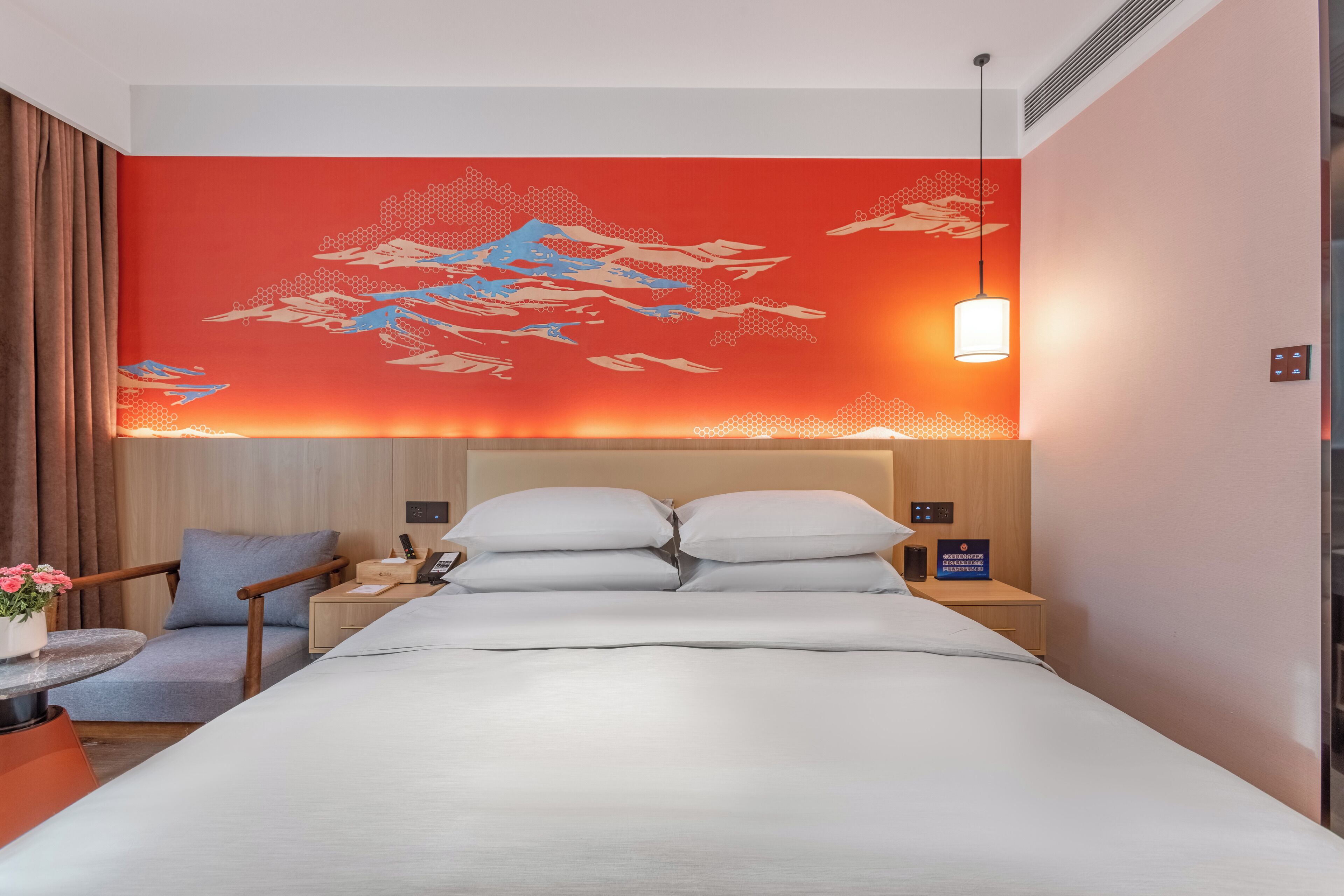 Una habitación de hotel con una cama, una mesita de noche, una silla y una pared con un diseño rojo.