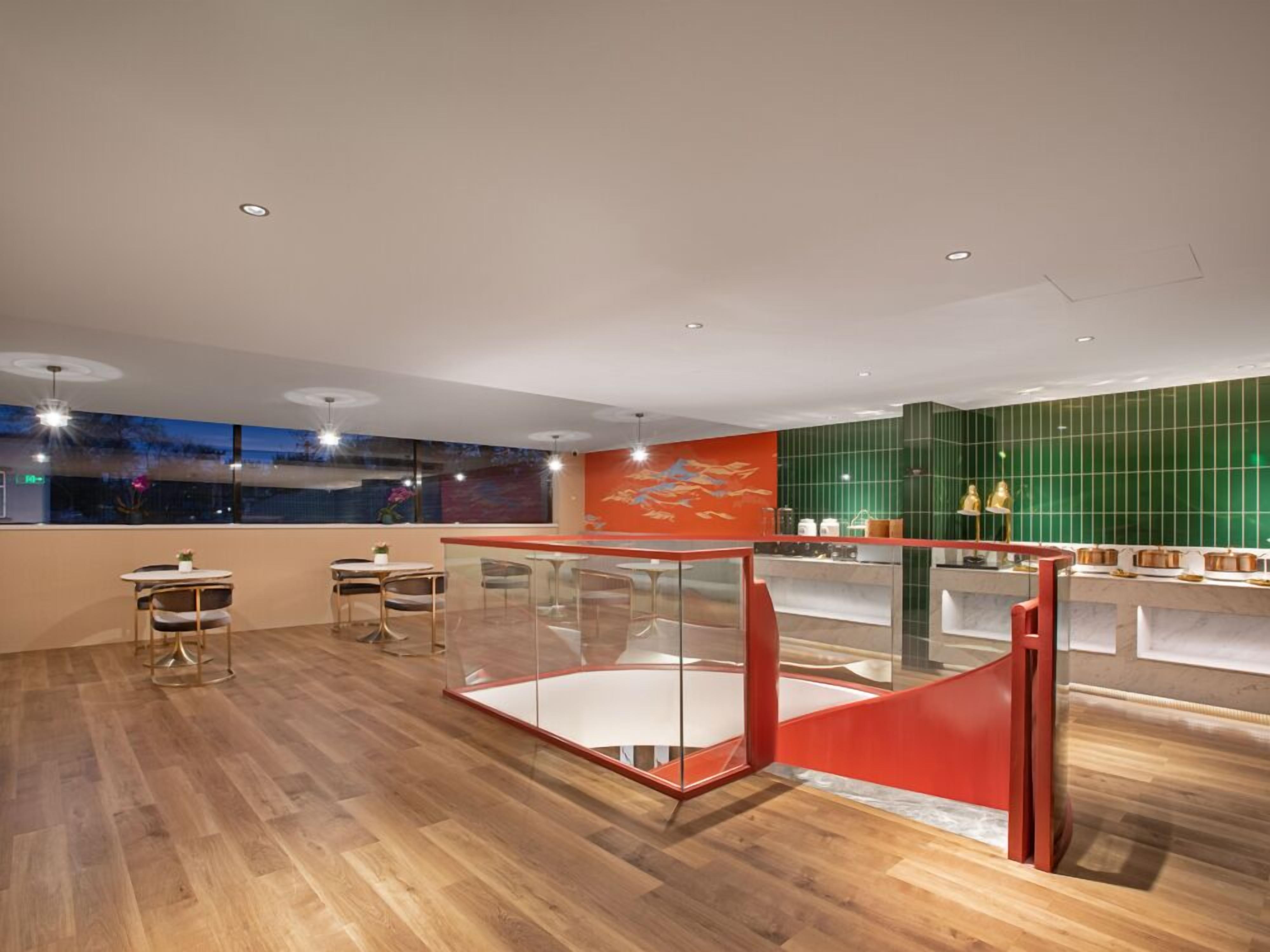 Un interior moderno con suelo de madera, un panel de vidrio y una pared de azulejos verdes.